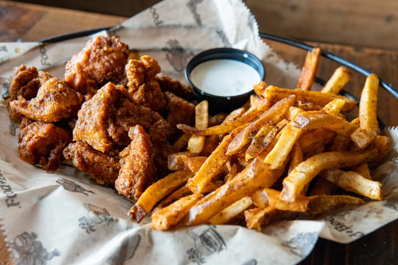 Basket of fried boneless wings and seasoned French fries with a side of jalapeno ranch