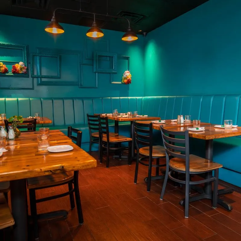 Dining room with blue walls, blue booth seating and wooden tabletops.