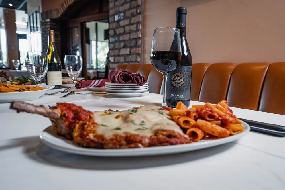 Veal chop Parmigiana with rigatoni and a bottle of red wine in the dining room