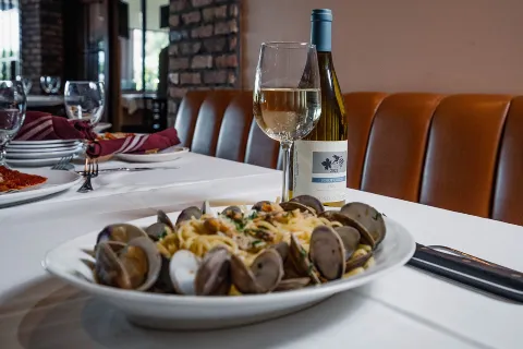 Linguine with clams served in the dining room, with a bottle of white wine