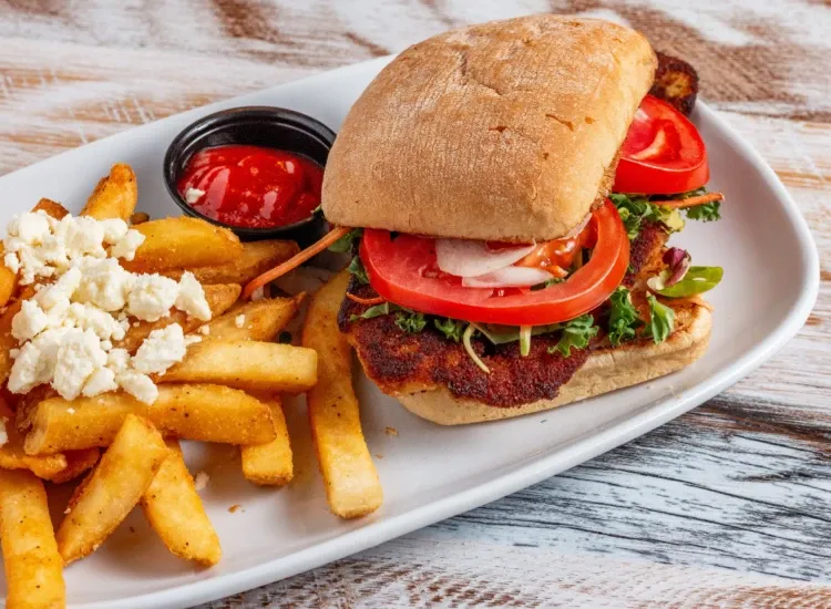 Athenian fish sandwich on ciabatta bread topped with mixed vegetable slaw, tomatoes, and onions, served with Greek fries and dipping sauce.