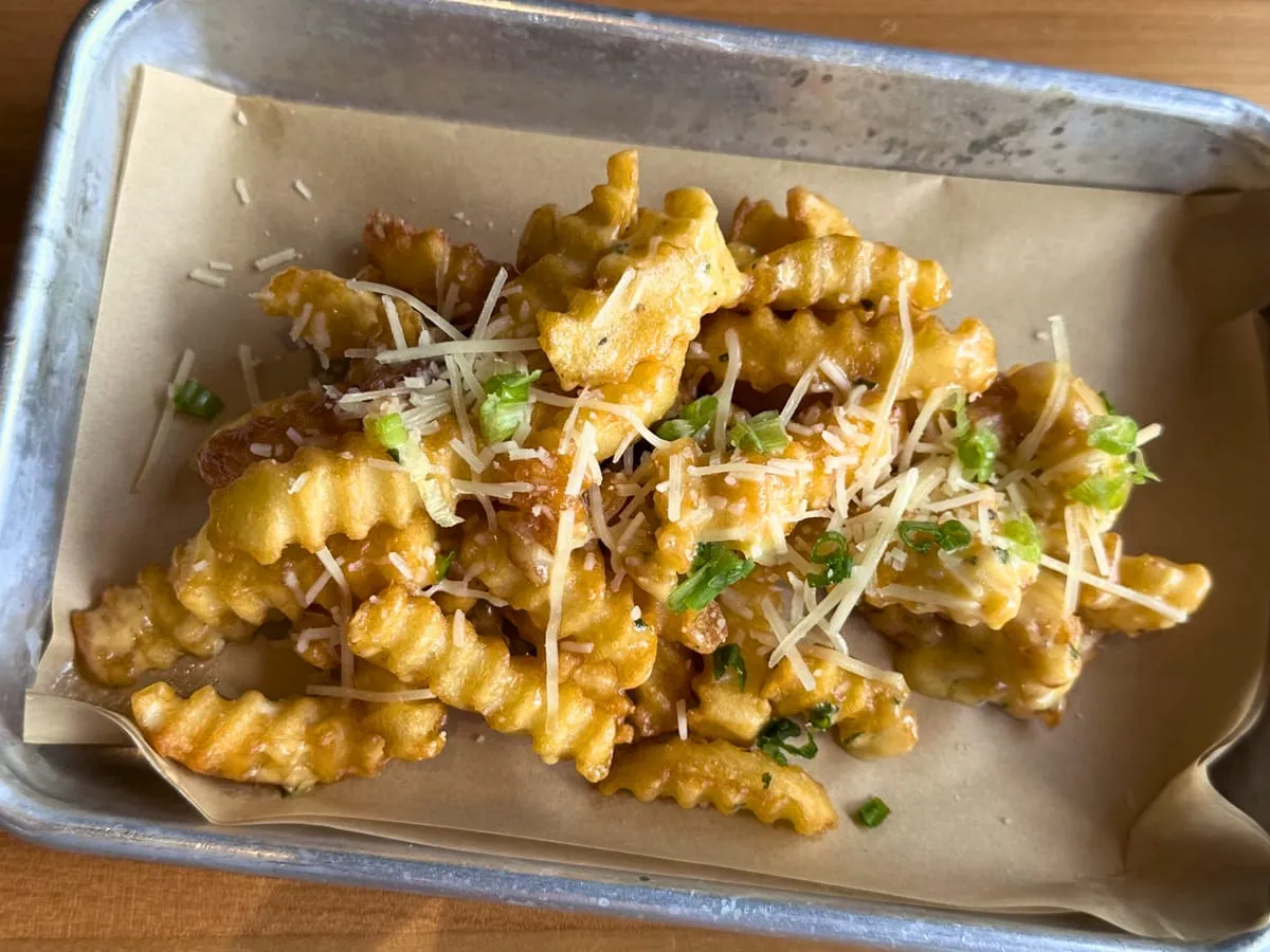 Ball Park Fries, crinkle-cut and topped with shredded Parmesan and green onions, in a paper-lined metal tray