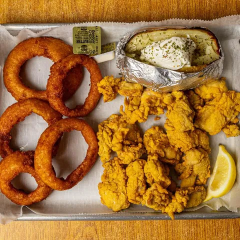 Fried oysters with baked potato and onion rings.
