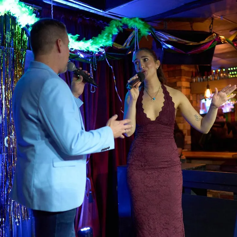 Two people singing on stage with microphones.