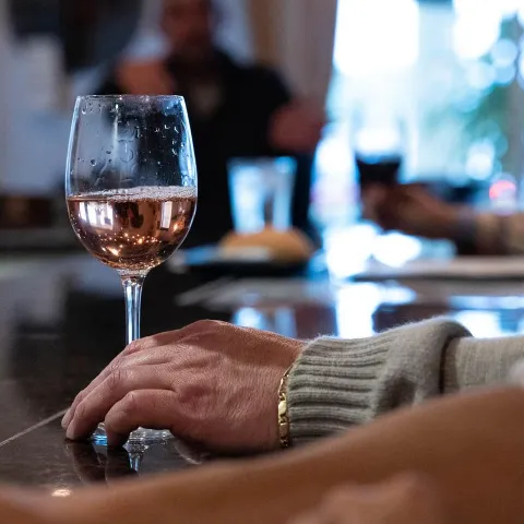Close up shot of bar counter, customer's hands with a served glass of  white wine.
