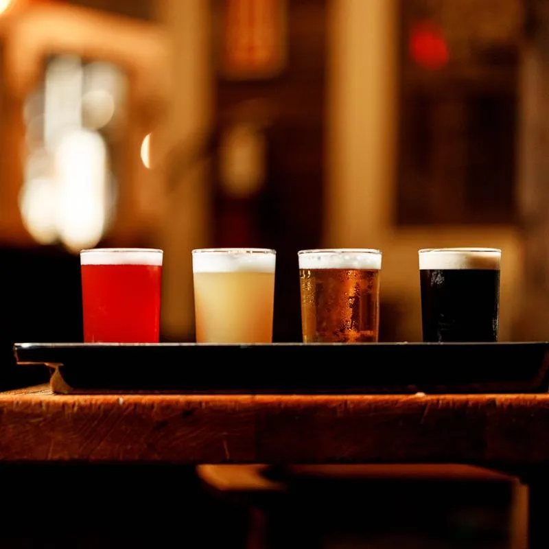 Beer flight on a wooden table against a blurry background.