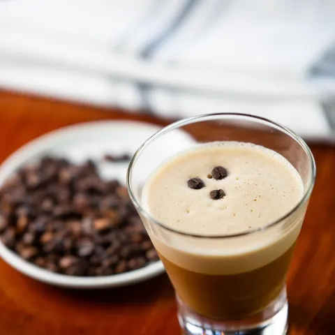 Glass of coffee and a plate with coffee beans