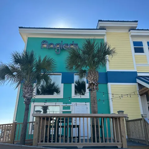 Colorful restaurant exterior with palm trees.