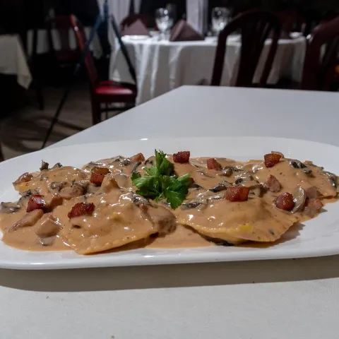 Ravioli smothered in truffle cream sauce, topped with mushrooms