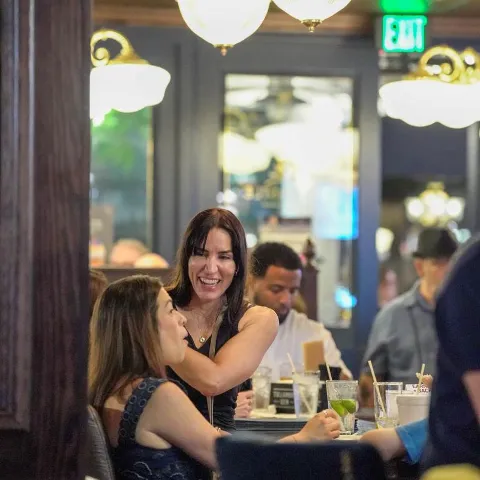 Friends laughing and enjoying drinks at a bar.