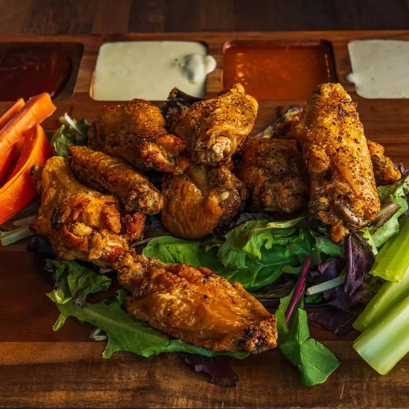 Lemon Pepper wings served with celery, carrots, and various sauces for dipping.