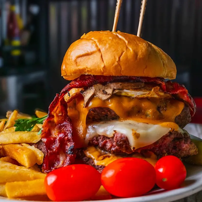 Double cheeseburger with bacon, fried egg, fries, and grape tomatoes.