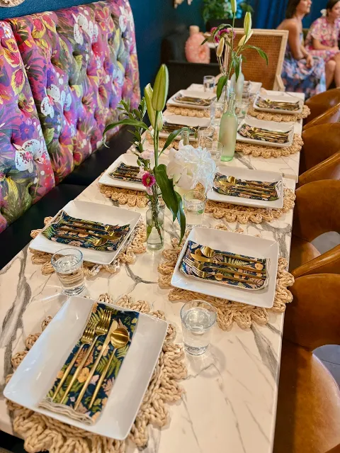 A long table set with gold flatware and floral centerpieces