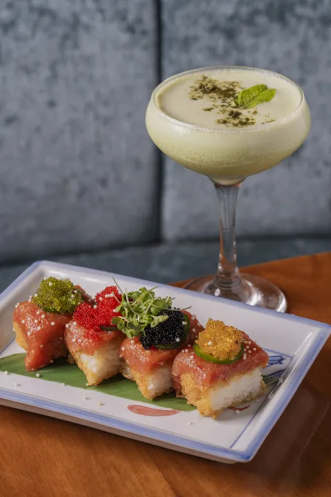 Four pieces of crispy rice with spicy tuna topped with assorted roe a creamy green cocktail