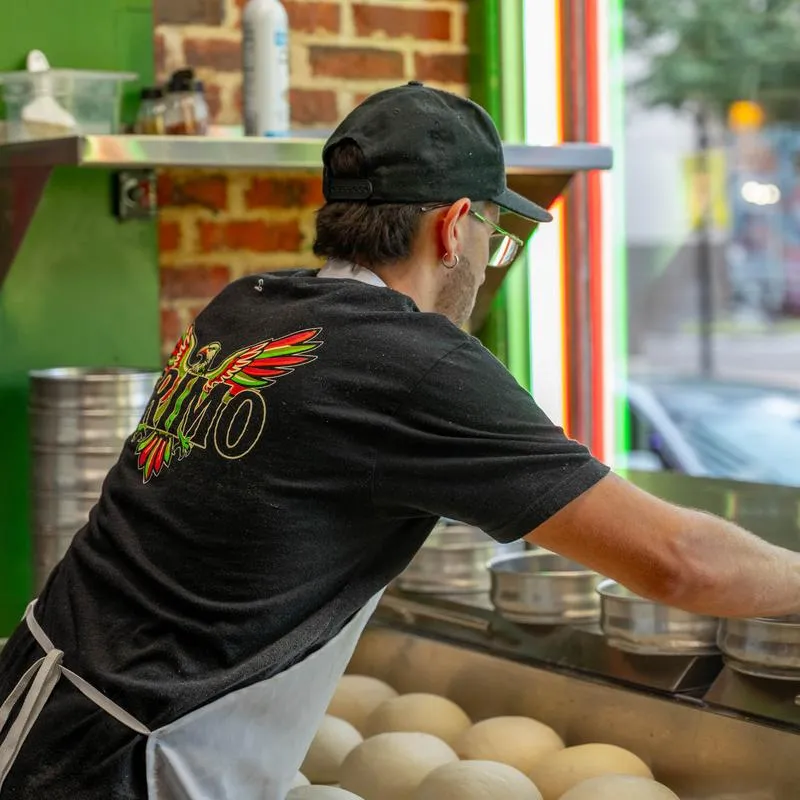 Person preparing dough behind a restaurant counter.