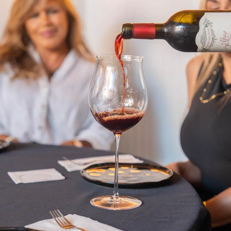 Wine service, a server pours a glass of wine for a guest at table.