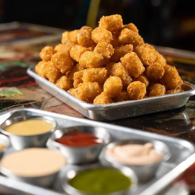 Different dipping sauces with tater tot plate in background