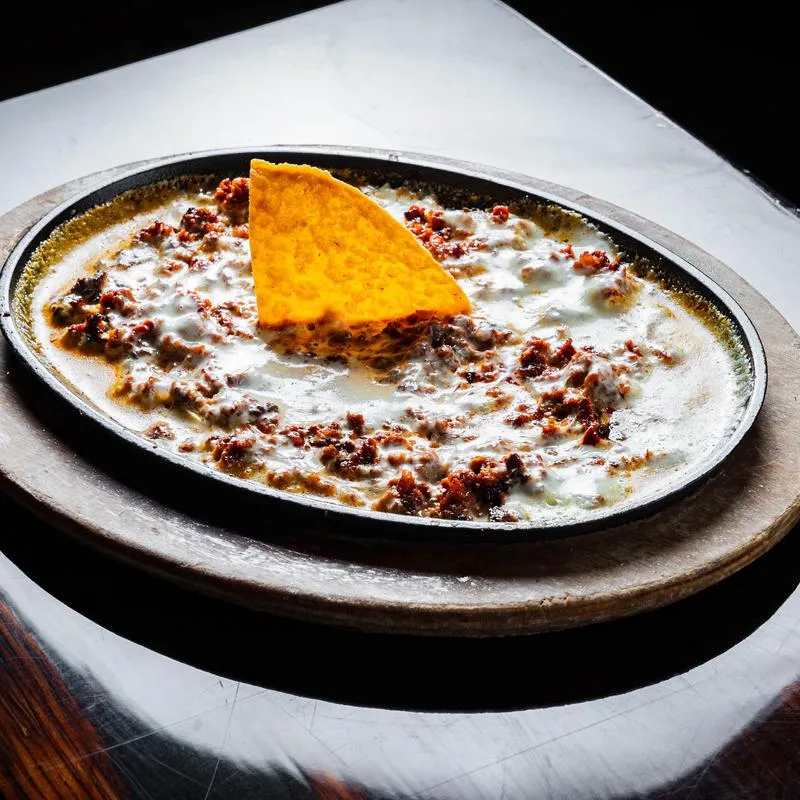 Mozzarella cheese and chorizo over a skillet, served with tortillas.