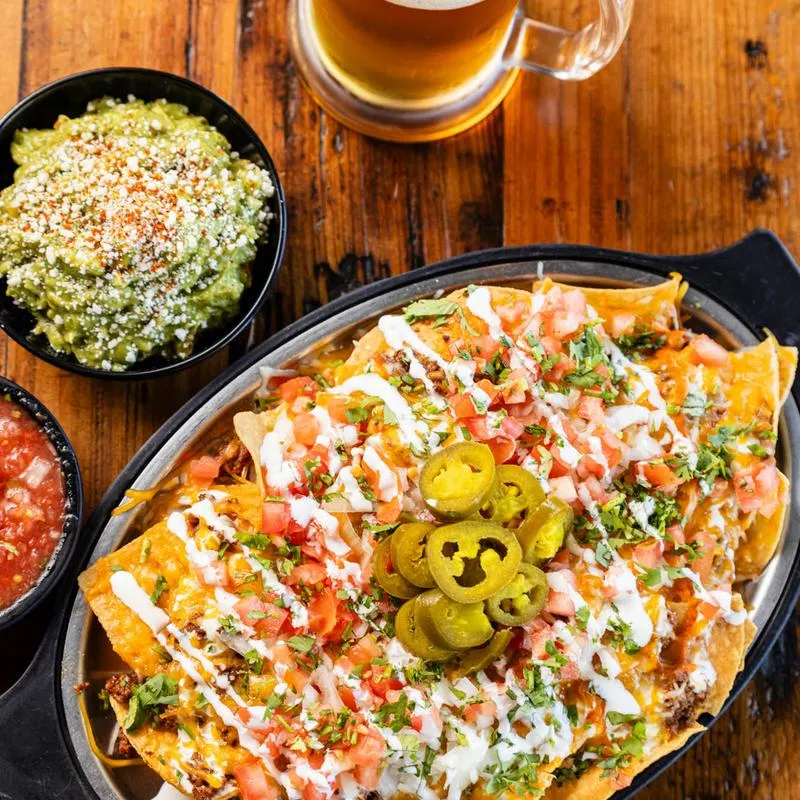 Loaded nachos guacamole, salsa, and beer, top view.