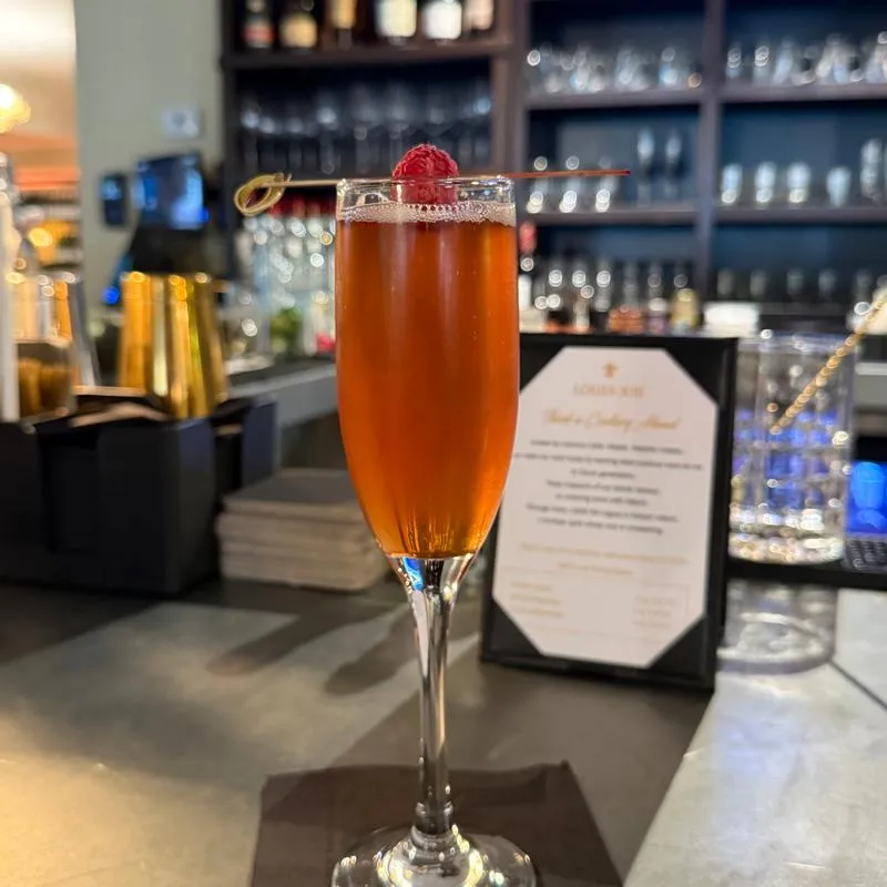 Cocktail served in a flute glass, garnished with a cherry.