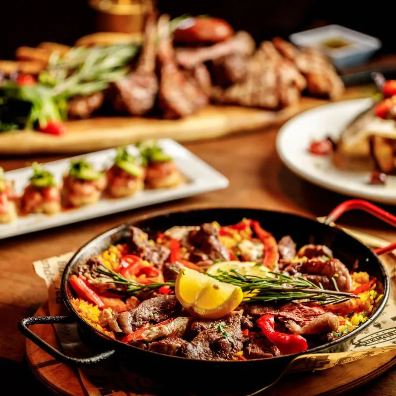 Mixed meat paella surrounded by various dishes.