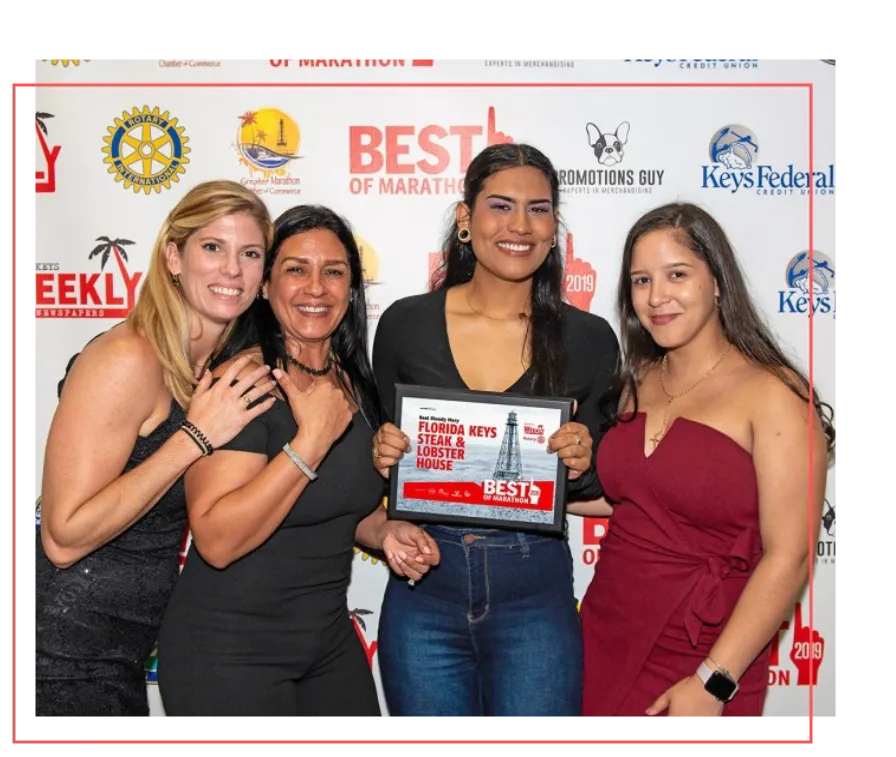 Four women smiling while holding award plaque