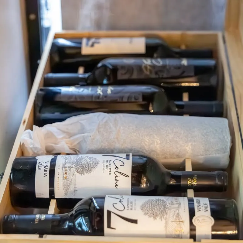 Assorted red wine bottles in a crate.