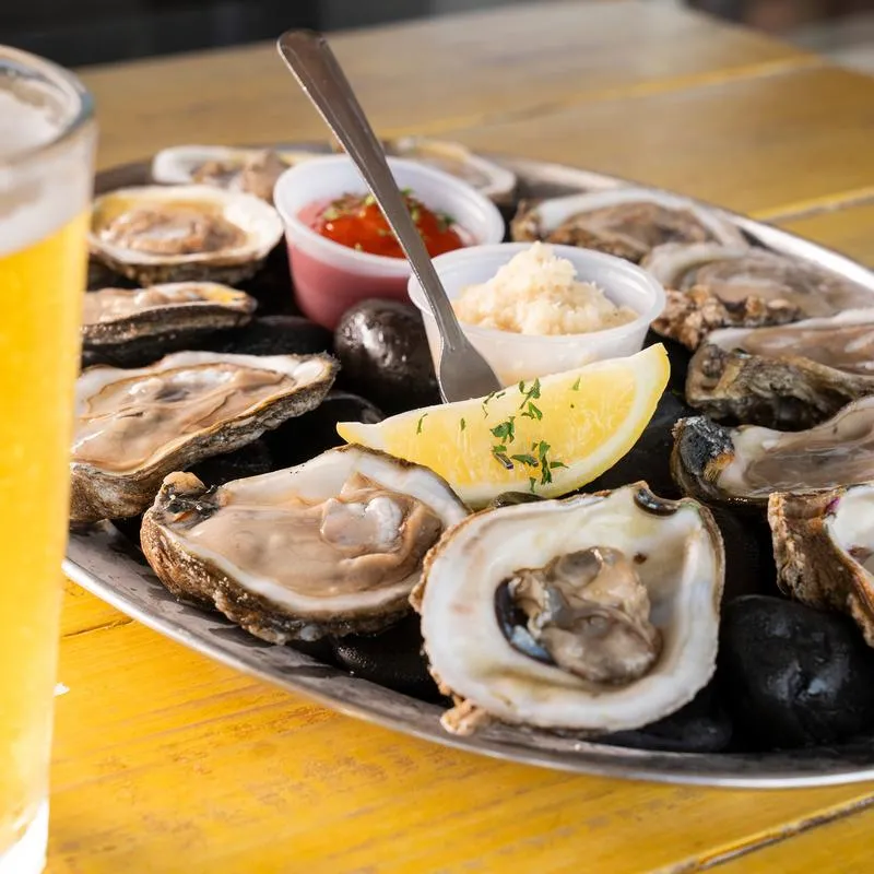 Platter of raw oysters, served with dwo sauces and lemon wedge.