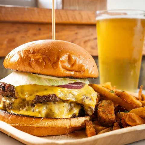 Corey Avenue Burger served with fries, alongside glass of beer.