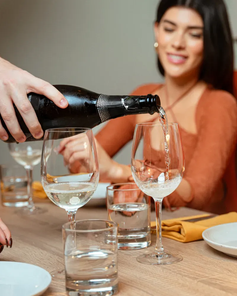 A woman pours a glass of white wine.