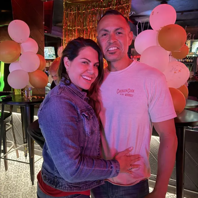 A couple smiling together in bar area decorated with balloons.