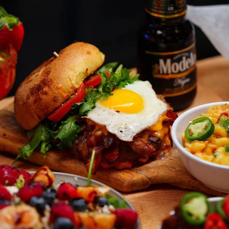 Mondragon burger served on a wooden board, alongside other dishes and drinks.