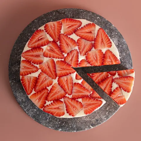 A sliced strawberry cake with a light sponge and cream layers, presented on a plate.
