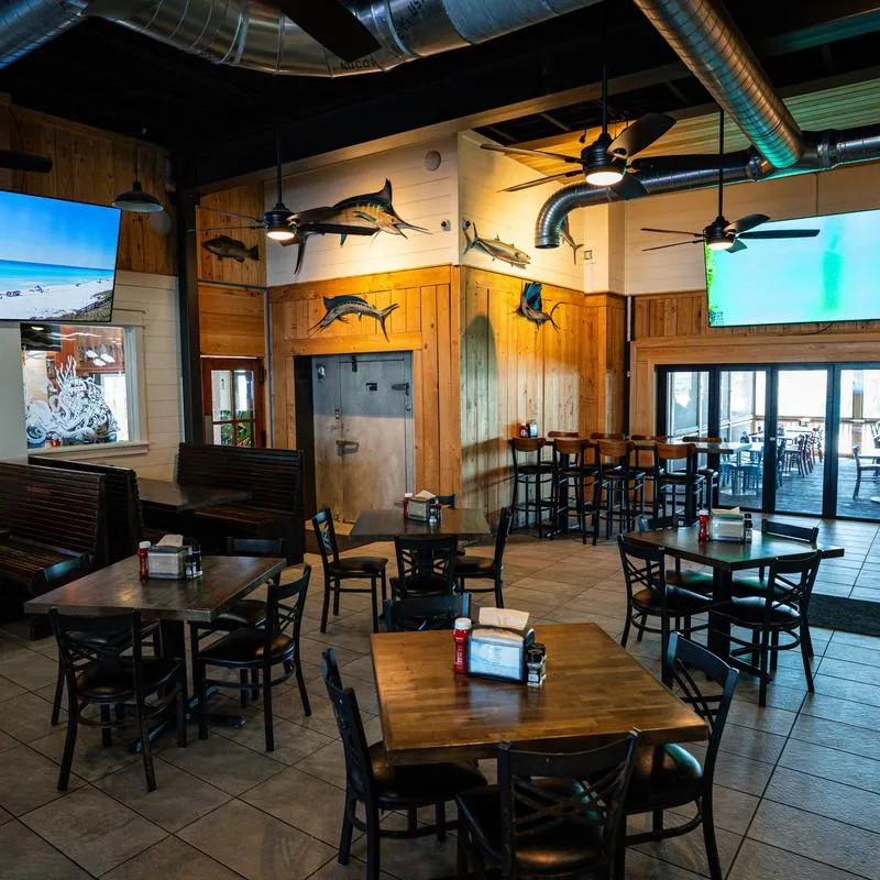 Interior with tiled flor, table seating, TV screens and maritime-themed decor.
