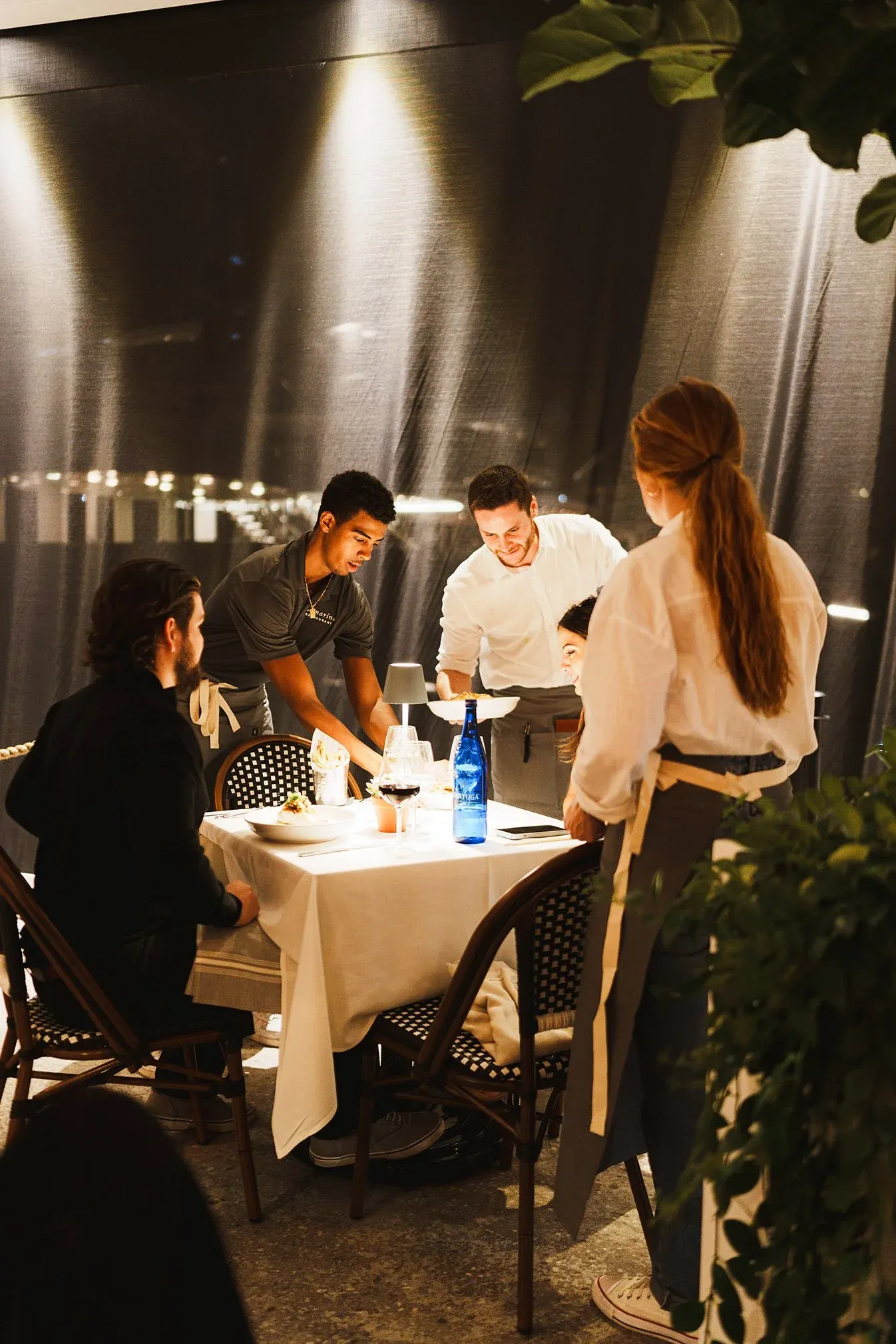 Restaurant scene with servers attending to seated guests at a table. best Restaurant in West Palm Beach for lunch
