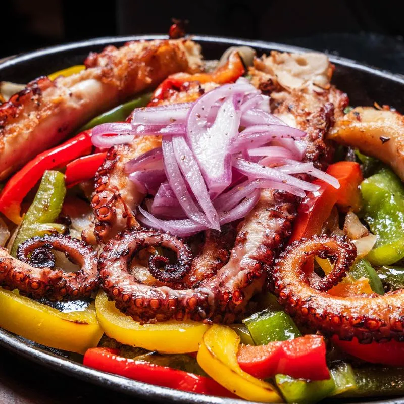 Grilled octopus served with sauteed peppers and fresh red onions.