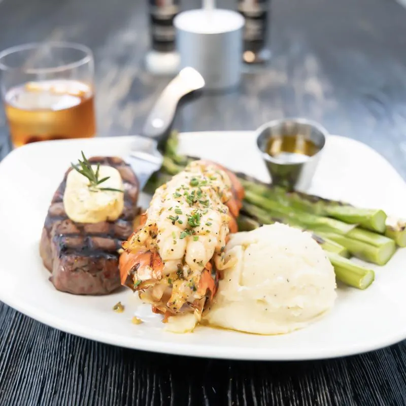Steak and lobster served with mashed potatoes and asparagus.