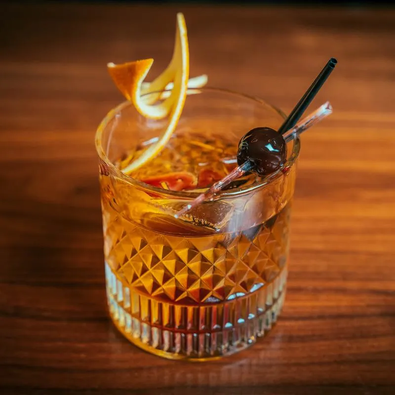 Old Fashioned cocktail with orange peel and cherry garnish