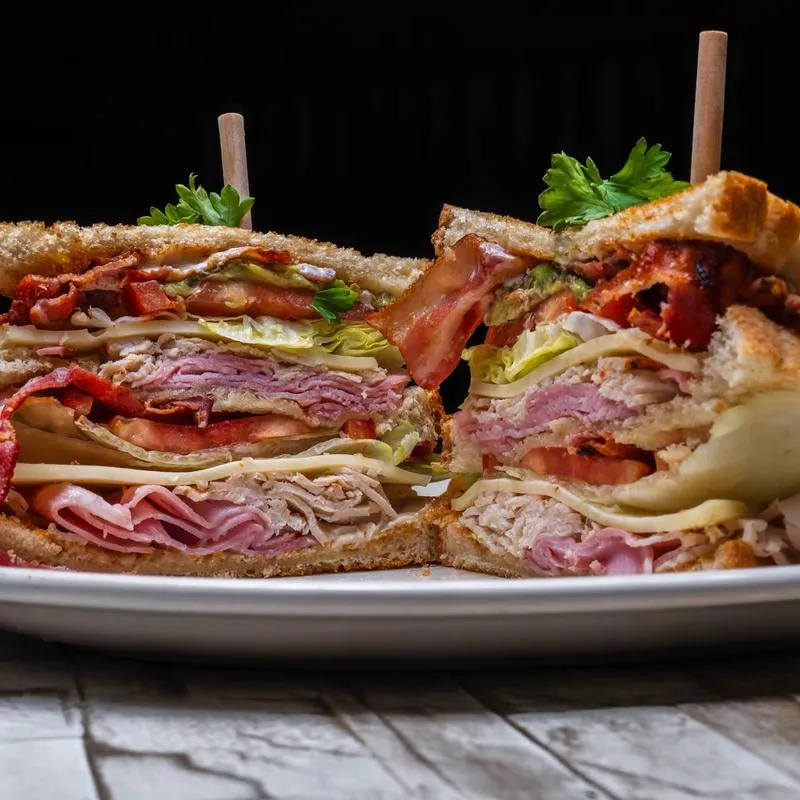 Cross-section of a club sandwich with turkey, ham, bacon, lettuce, and cheese.