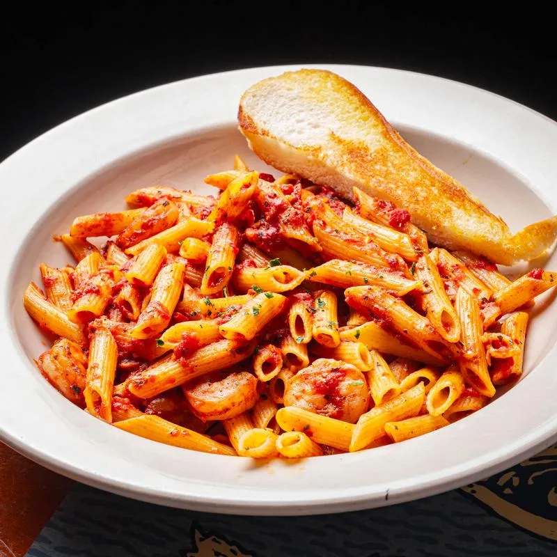 Shrimp and penne pasta in a spicy tomato sauce with a side of toast.