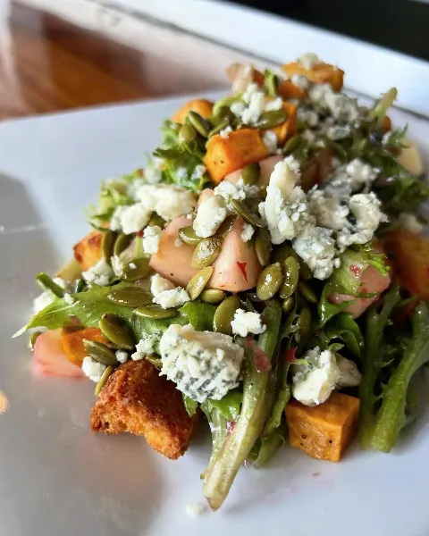 Dive into the flavors of fall with our Cranberry Harvest Salad. Crisp greens, juicy apples, roasted sweet potatoes, and cornbread croutons&mdash;topped with pumpkin seeds, Gorgonzola, and a tangy cran