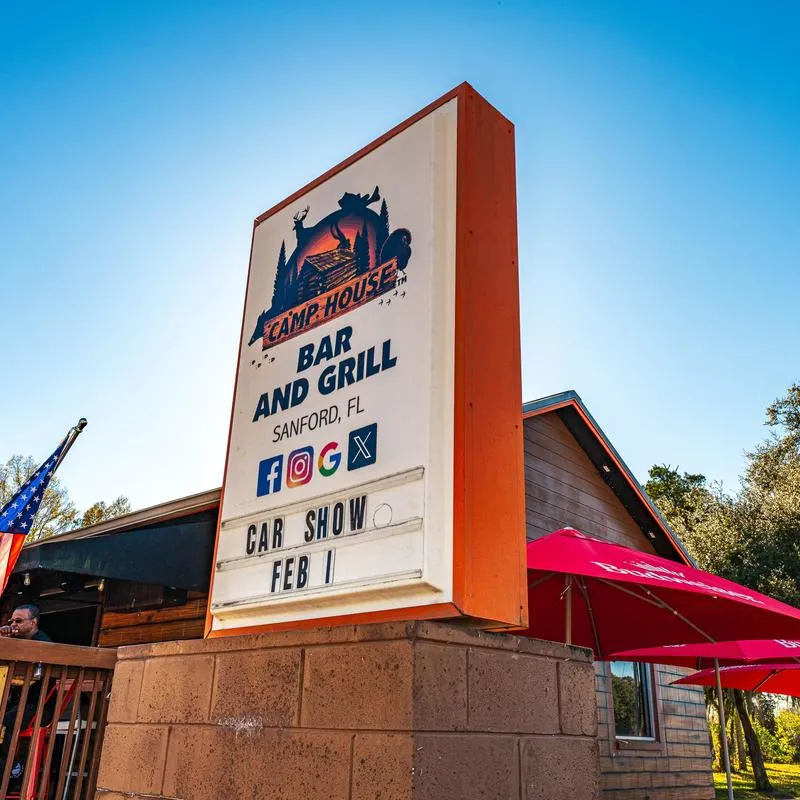Camp House Bar and Grill sign with against a clear blue sky.
