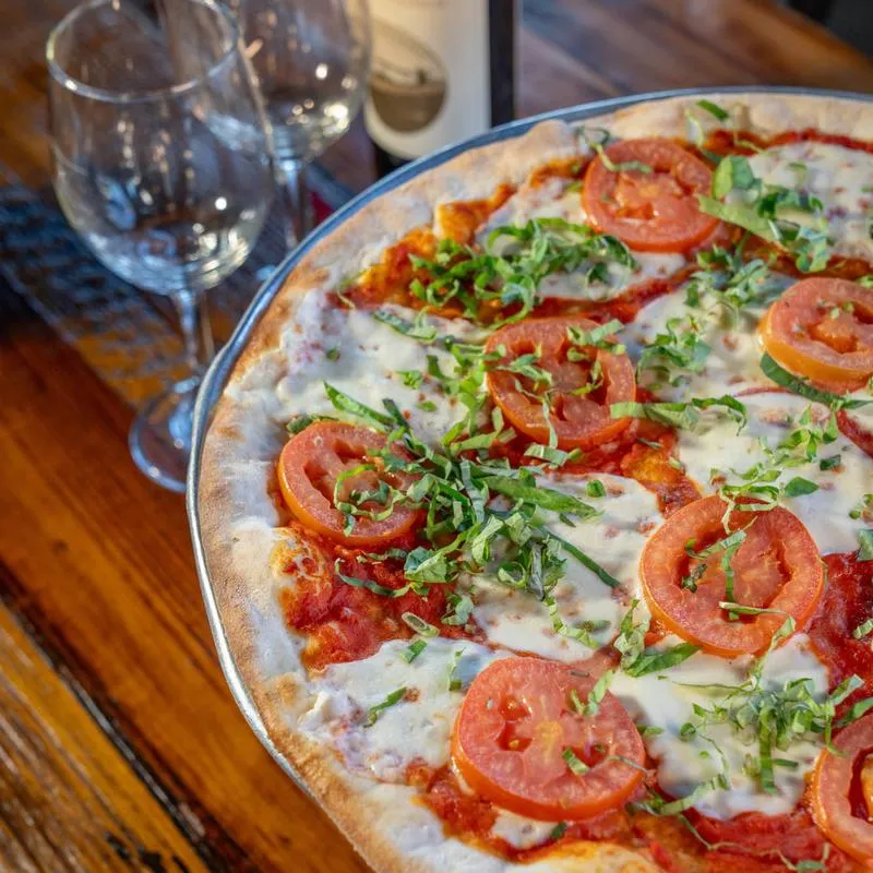 Margherita pizza topped with tomatoes, melted cheese, and fresh basil.