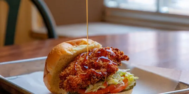 A Person Pouring A Liquid Into A Sandwich
