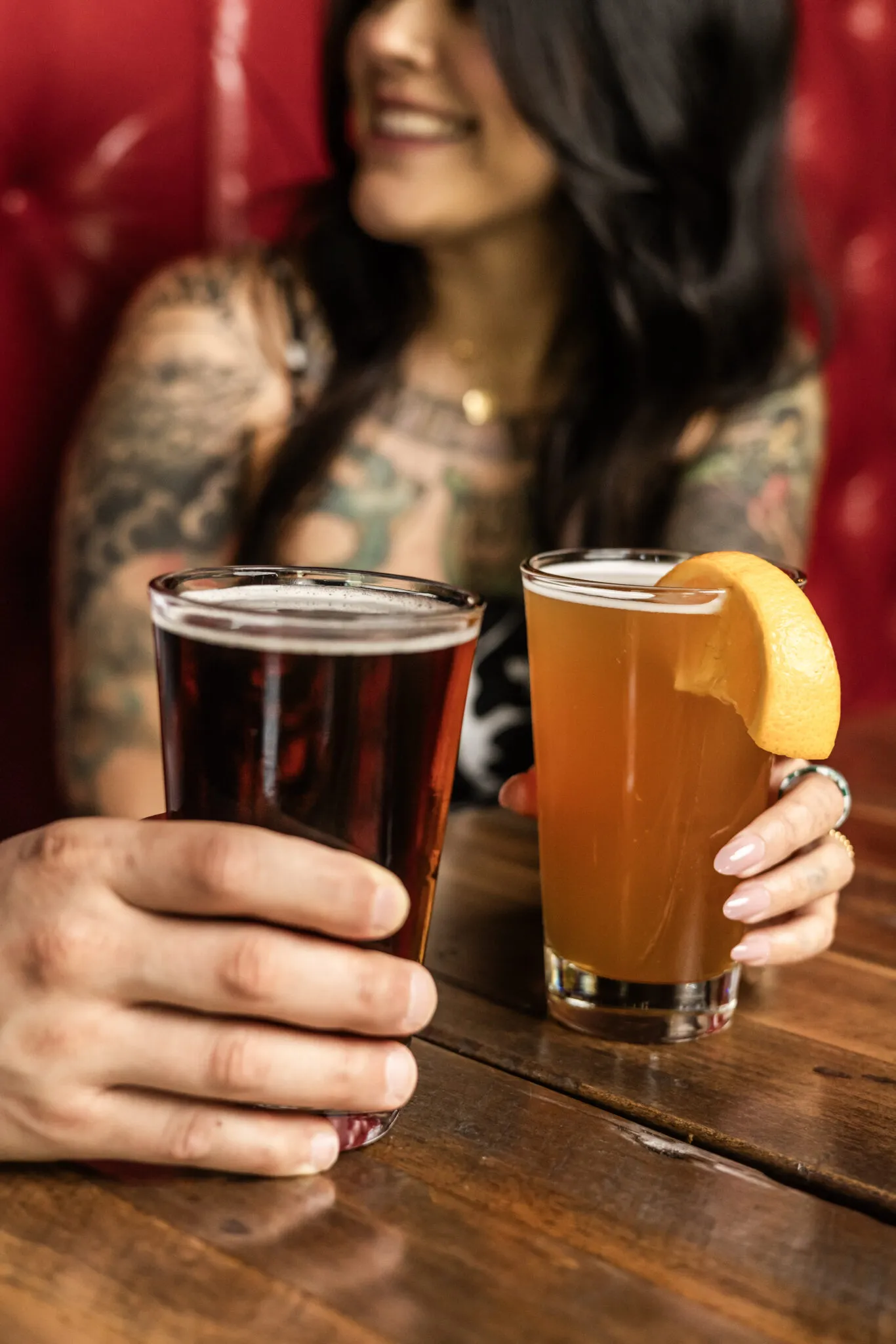 Tattooed person holding dark and citrus beers