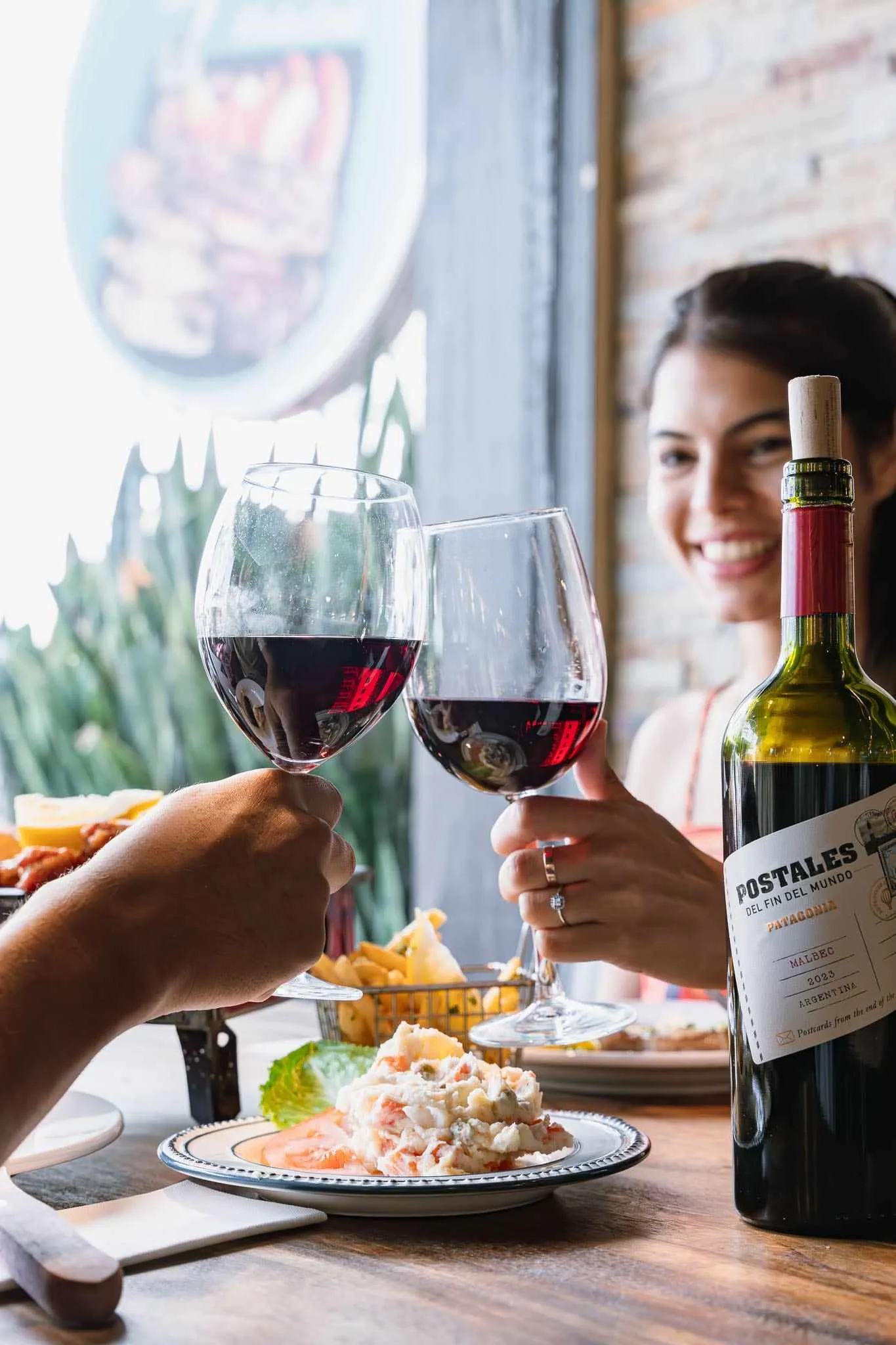 Two friends clinking glasses of red wine at the table