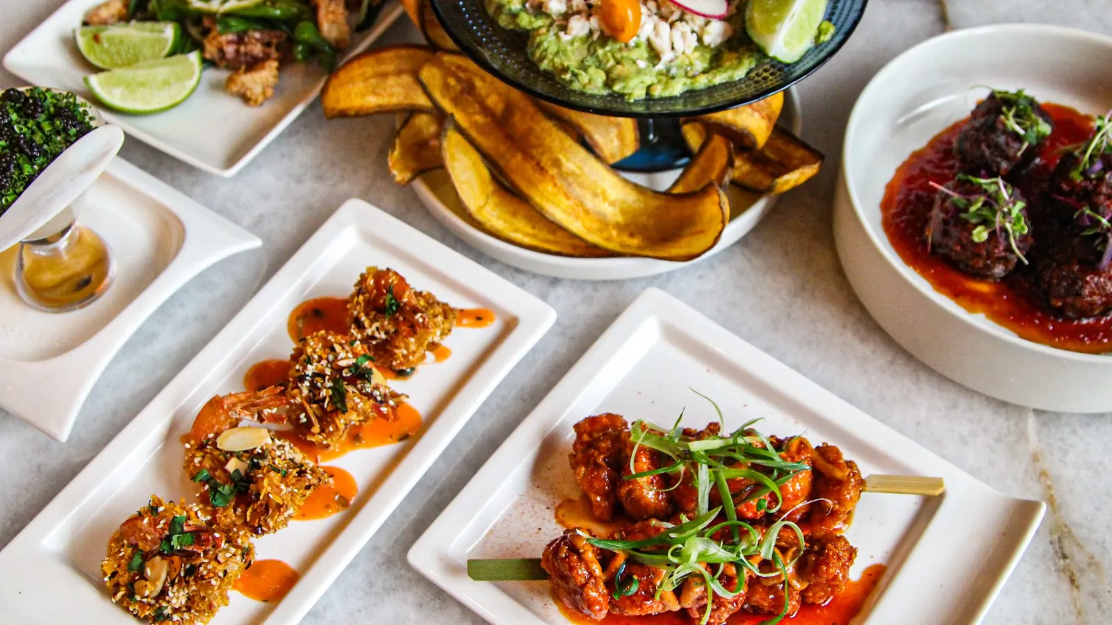 combination of happy hour food including hot and crunchy shrimp topped with slivered almond, hot honey chicken bites on skewers with shaved green onion, prime meatballs in house made steak sauce dress