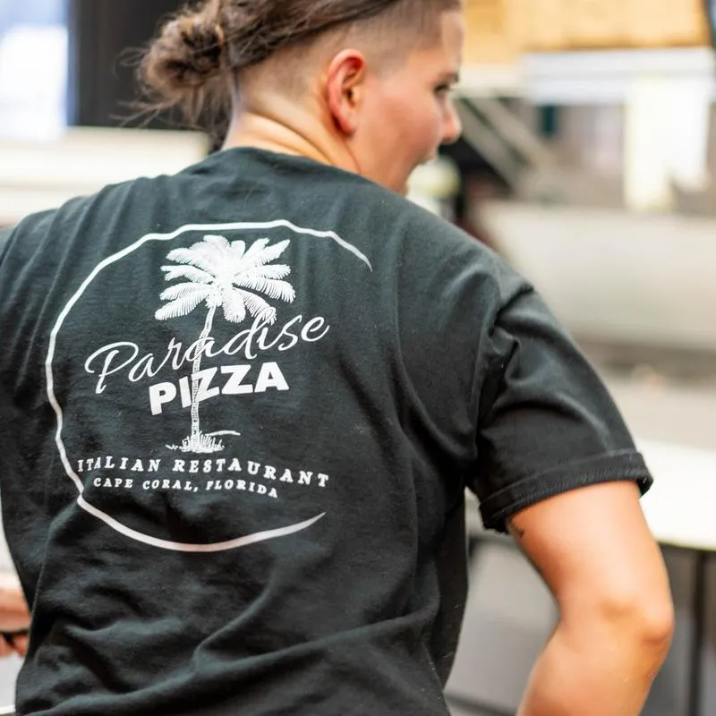 A kitchen employee wearing Paradise Pizza t-shirt.