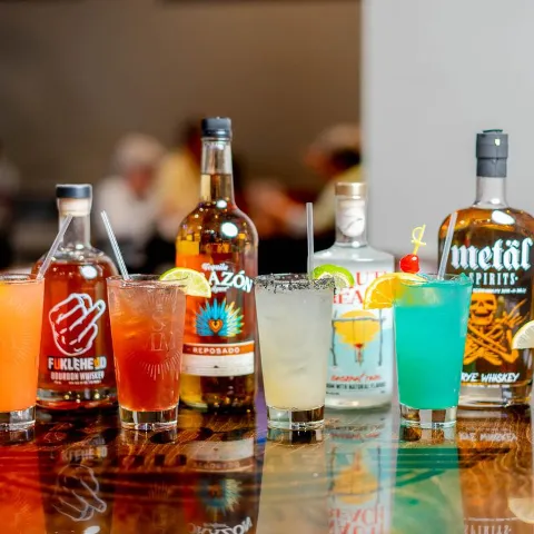 Colorful cocktails and liquor bottles on a counter.