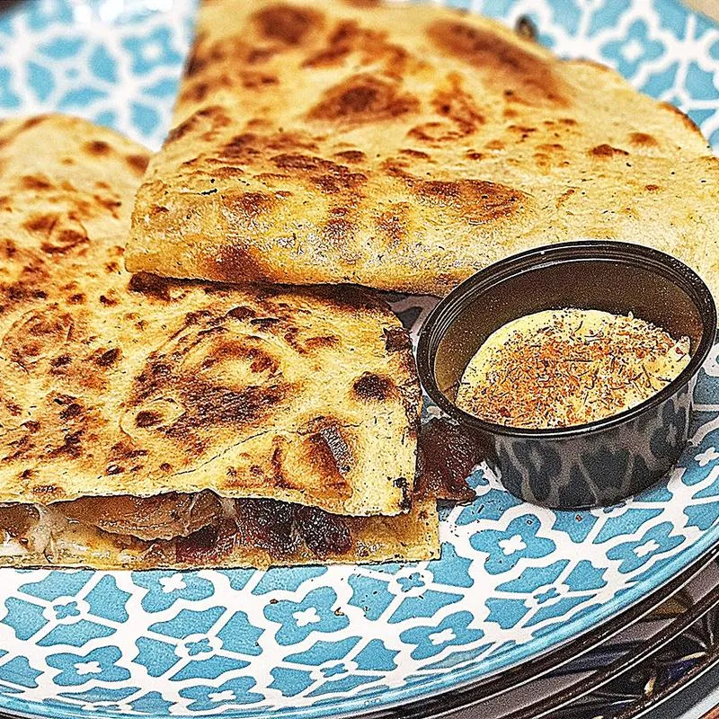 Cajun shrimp folded inside toasted flatbread, with seasoning on the side.
